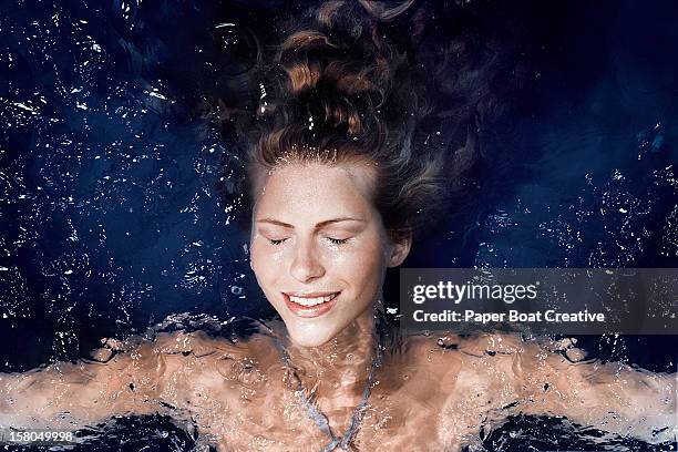 woman floating in the pool of a spa - woman pool relax fotografías e imágenes de stock