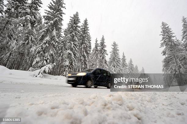 Cars drive on a snowy road near Neuhaus am Rennweg, eastern Germany, on December 10, 2012. Heavy snowfalls in the region caused chaos on road and...