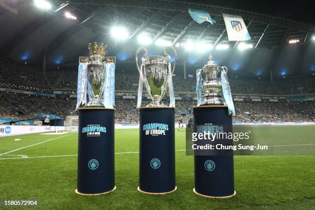 The Premier League trophy, Champions League trophy and FA Cup trophy are seen next to the pitch prior to the preseason friendly match between...