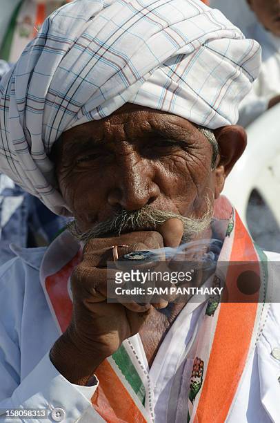 Congress party supporter puffs a traditional pipe during a political rally addressed by Congress president Sonia Gandhi ahead of the Gujarat Assembly...