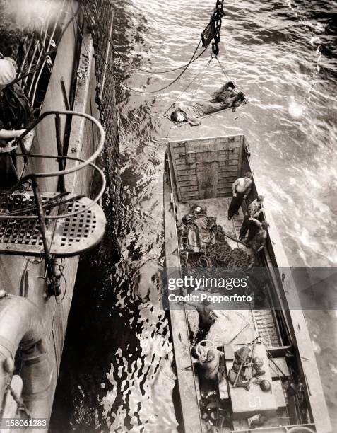 Wounded soldiers from the invasion of Bougainville are hoisted from a lighter to a transport vessel during World War Two, circa November 1943. This...