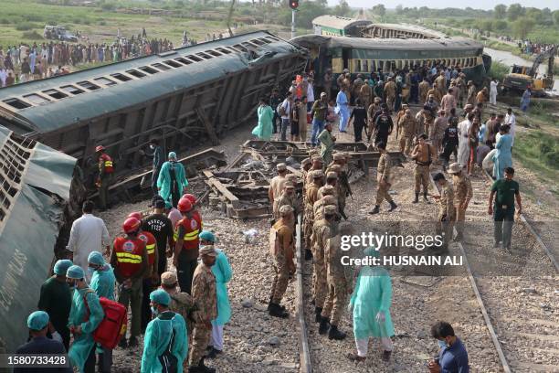 Paramilitary rangers and volunteers inspect the carriages at the accident site following the derailment of a passenger train in Nawabshah on August...