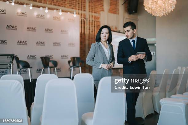 asian chinese businesswoman final check going through programme details with banquet hall manager before the business conference seminar begin - banquet hall stockfoto's en -beelden