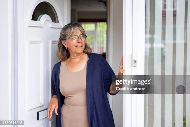 mujer parada en la puerta de su casa y mirando hacia otro lado - entrometido fotografías e imágenes de stock