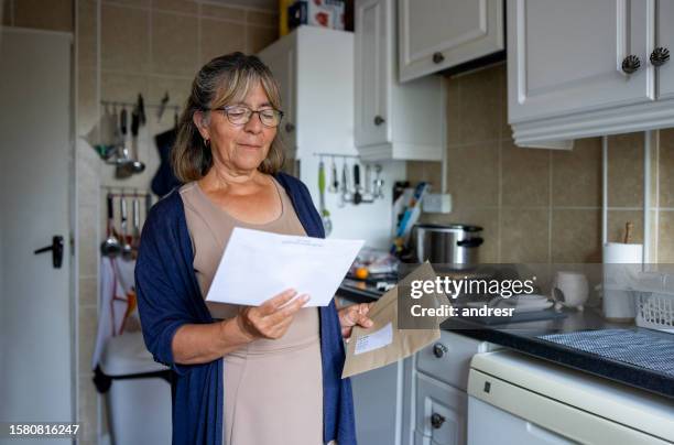 senior woman at home checking her mail - receiving check stock pictures, royalty-free photos & images