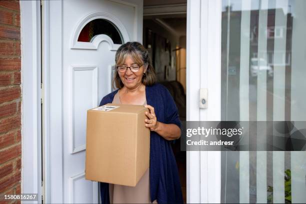 mature woman at home receiving a package - home delivery stock pictures, royalty-free photos & images