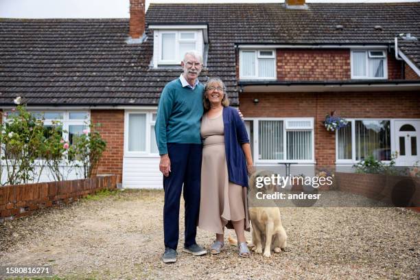 glückliches älteres paar vor ihrem haus mit ihrem hund - council estate uk stock-fotos und bilder