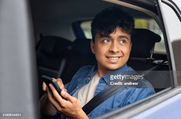 fahrgast fährt in einem crowdsourcing-taxi und schreibt sms auf seinem handy - constituency stock-fotos und bilder