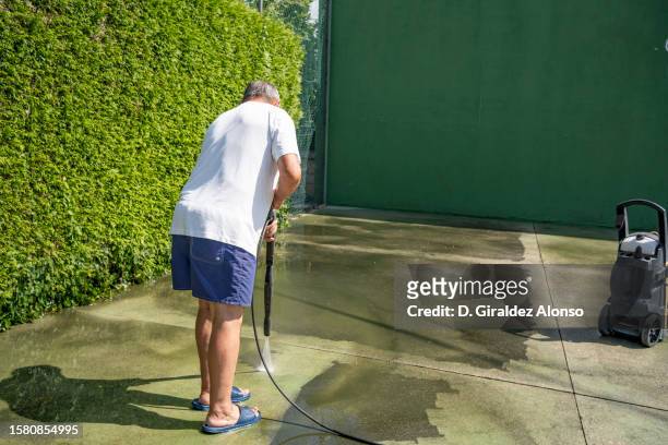 senior man washes the floor of a tennis court - rainwater basin stock pictures, royalty-free photos & images