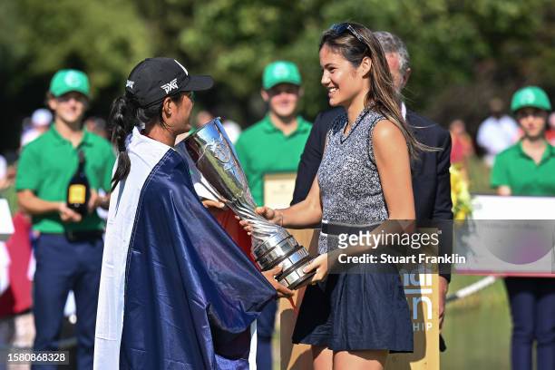 Celine Boutier of France is presented with the Amundi Evian Championship trophy by British tennis player Emma Raducanu following victory in the...