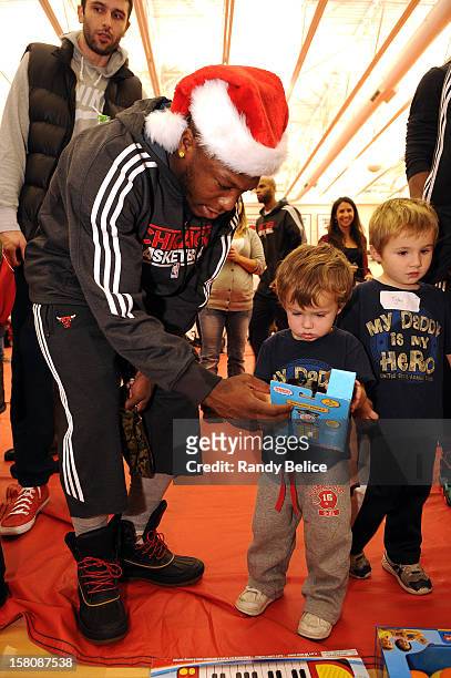 Nate Robinson of the Chicago Bulls assists a partygoer with selecting a toy during the team's USO / Chicago Housing Authority Holiday Party on...