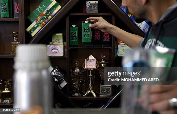 Palestinian employee of the "Stay Stylish" shop displays packaged M75 perfume bottles in Gaza City on December 10, 2012. "Victory" has never smelled...