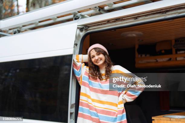 woman standing in the camper van in the forest in autumn - november stockfoto's en -beelden