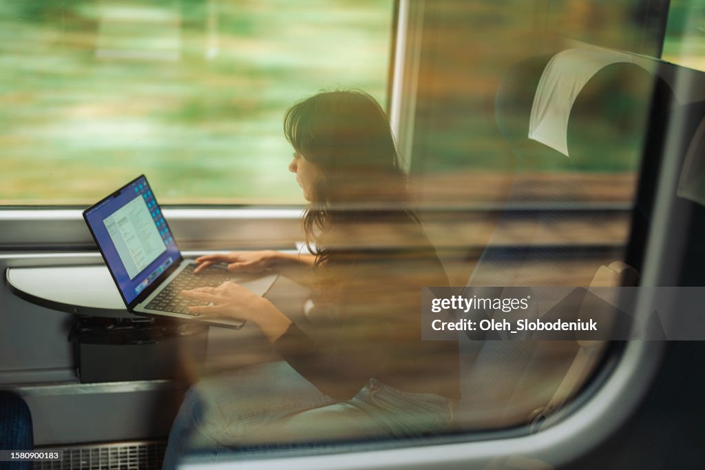 Frau, die mit Laptop arbeitet, während sie mit dem Zug reist