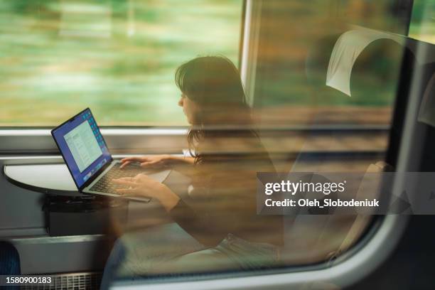 woman working with laptop while traveling by train - carruagem imagens e fotografias de stock