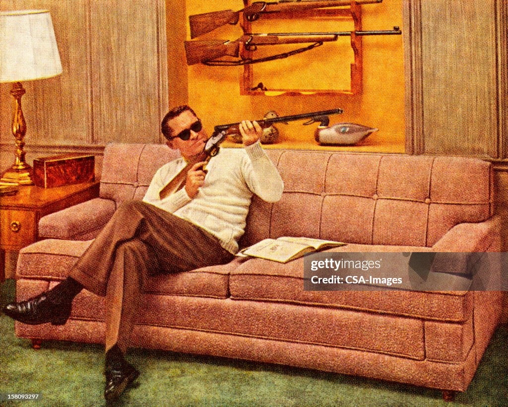 Man Wearing Sunglasses and Holding Gun