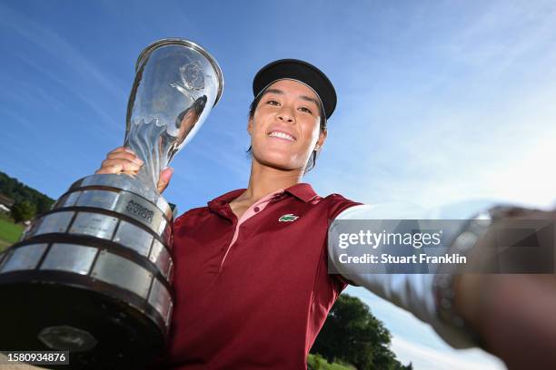 Celine Boutier of France imitates a selfie as she poses with the Amundi Evian Championship trophy following victory in the Final Round of the Amundi...