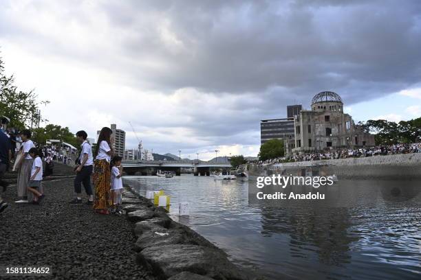 People attend the Peace Message Lantern Floating Ceremony at the Hiroshima Peace Memorial Park to pay tribute to the atomic bomb victims in...