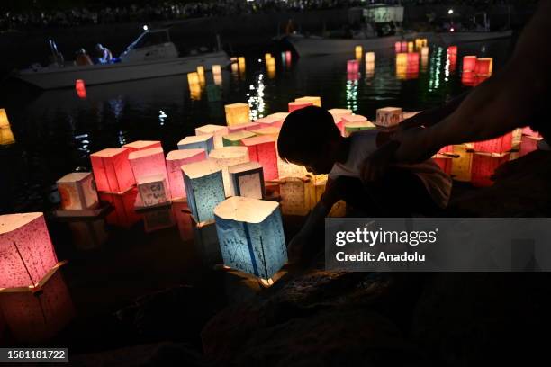 People attend the Peace Message Lantern Floating Ceremony at the Hiroshima Peace Memorial Park to pay tribute to the atomic bomb victims in...