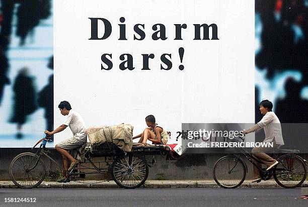 People ride past a SARS billboard in Beijing, 24 July 2003. Chinese Vice Premier Wu Yi, addressing a gathering of Asian and European economic...