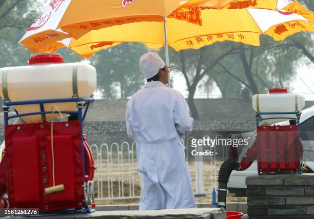 Chinese health worker waits to disinfect vehicles leaving the hospital erected in barely a week to house a rapidly increasing number of Chinese...
