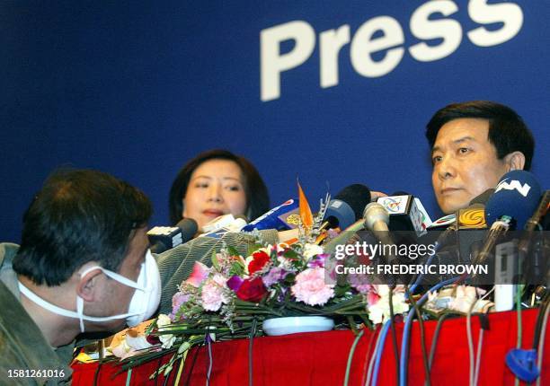Journalist adjusts a microphone facing Cai Fuchao , propaganda chief for Beijing municipality, 25 April 2003, during a press briefing by the Beijing...