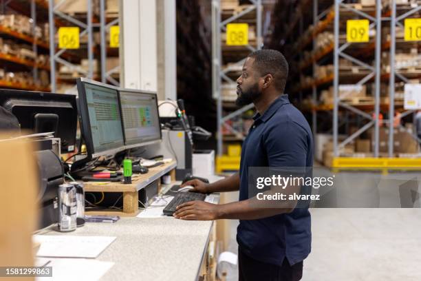 mann arbeitet am computer in großem fabriklager - fracht stock-fotos und bilder
