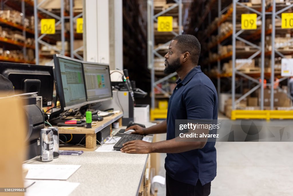 Man working on computer in large factory warehouse