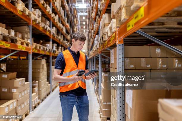 young man working at distribution warehouse - sala de armazenamento imagens e fotografias de stock