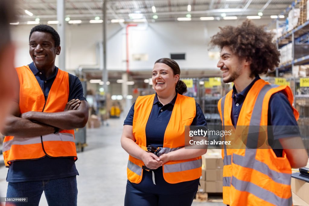 Smiling warehouse workers discussing work together on shopfloor