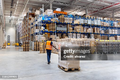 Young warehouse worker pulling pallet jack with boxes Young warehouse worker pulling pallet jack with boxes