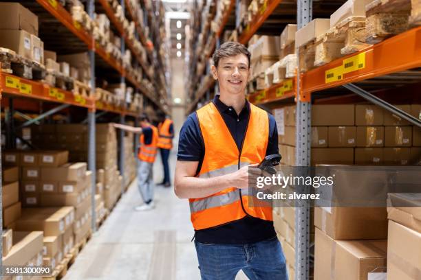 retrato de un joven feliz que trabaja en un gran almacén de distribución - trabajador de almacén fotografías e imágenes de stock