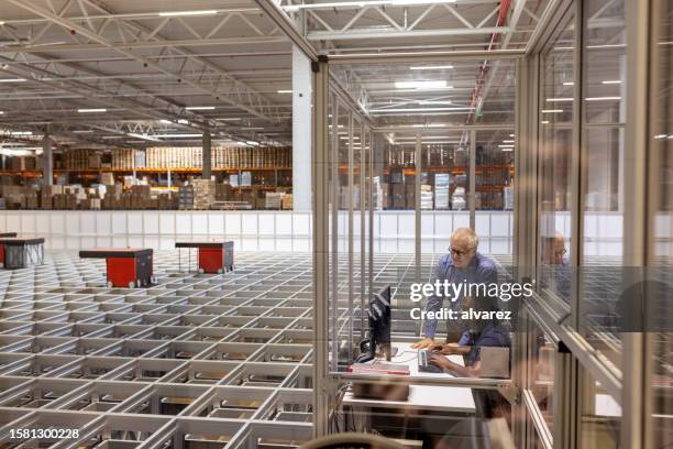 mann, der das fts im kontrollraum des lagers bedient, während der manager bereitsteht - autonome technologie stock-fotos und bilder