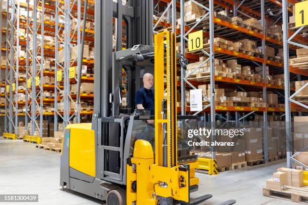 worker working on forklift loading machine in distribution warehouse - arranging stock pictures, royalty-free photos & images