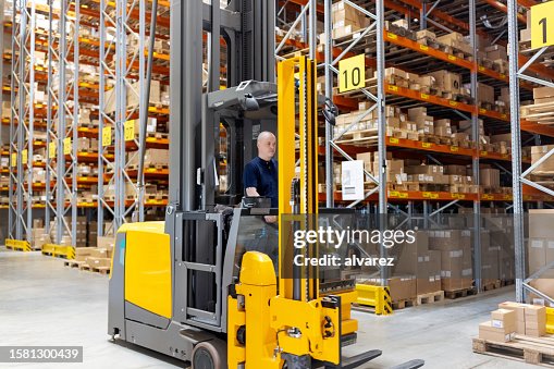 Worker working on forklift loading machine in distribution warehouse Worker working on forklift loading machine in distribution warehouse