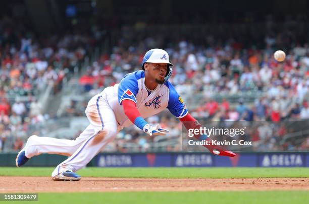 Orlando Arcia of the Atlanta Braves dives just before being tagged out at third base on a single by Michael Harris II in the seventh inning against...