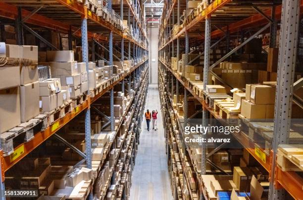 high angle view of a warehouse manager walking with foremen checking stock on racks - frakttransport bildbanksfoton och bilder