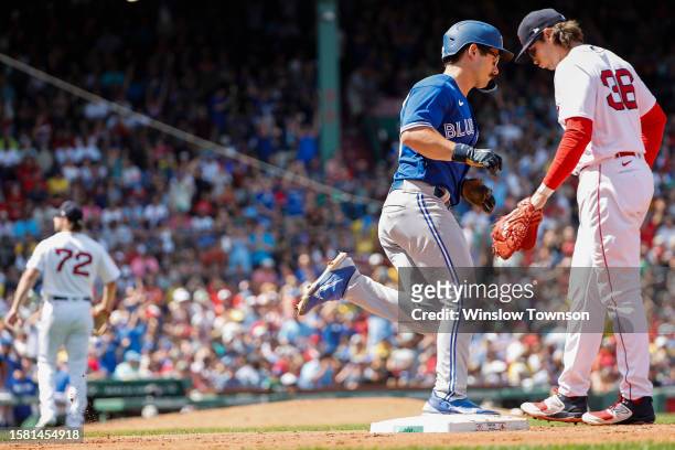 Davis Schneider of the Toronto Blue Jays rounds the bases past Triston Casas of the Boston Red Sox after his two-run home run off of pitcher Chris...