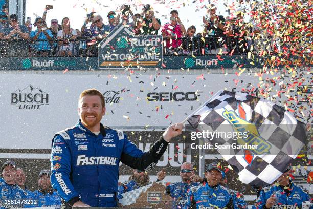 Chris Buescher, driver of the Fastenal Ford, celebrates with the checkered in victory lane after winning the NASCAR Cup Series Cook Out 400 at...