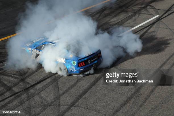 Chris Buescher, driver of the Fastenal Ford, celebrates with a burnout after winning the NASCAR Cup Series Cook Out 400 at Richmond Raceway on July...