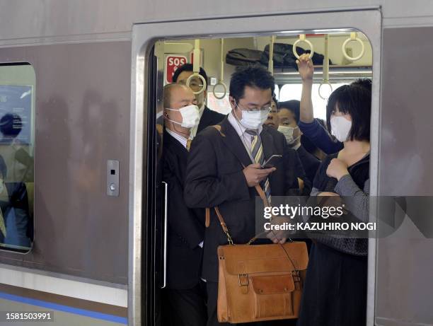 People wearing facemasks pack a train as they commute to work in Kobe, Hyogo prefecture, in western Japan on May 18, 2009. Japan shuttered more than...