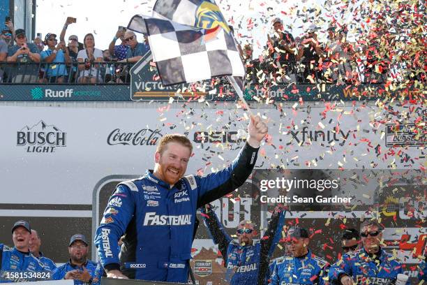 Chris Buescher, driver of the Fastenal Ford, celebrates with the checkered in victory lane after winning the NASCAR Cup Series Cook Out 400 at...
