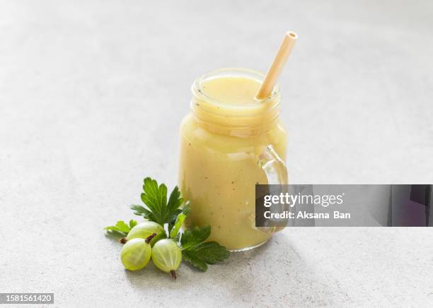 gooseberry drink, smoothie in a glass jar with a bamboo straw. light gray background. close up - uva spina foto e immagini stock