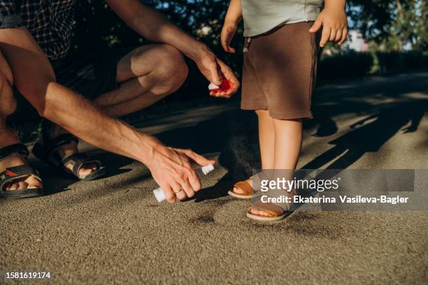 father applies mosquito spray to his son - motion sickness stock pictures, royalty-free photos & images