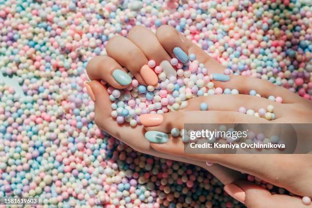 female hands with colorful polish nails. woman well-groomed hands with multicolor nails on salon table. manicure nail painting. - smalto per unghie foto e immagini stock