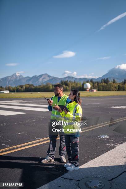 male and female airfield operation officers utilizing airfield landing and navigational aids - airport ground crew uniform stock pictures, royalty-free photos & images