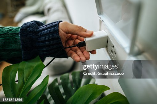 Men's hands are plugged in power outlet adapter cord charger of the smartphone Men's hands are plugged in power outlet adapter cord charger of the smartphone