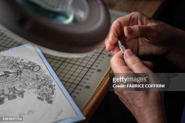 Swiss paper cutting artist Marianne Dubuis works on a piece at her home, in Chateau d'Oex, in the Prealps in western Switzerland on July 25, 2023....