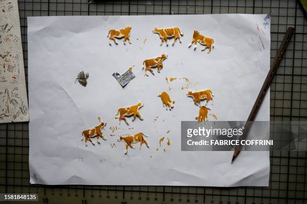 This photograph taken on July 25 shows little paper cut-out cows for a work by Swiss paper cutting artist Marianne Dubuis at her home, in Chateau...