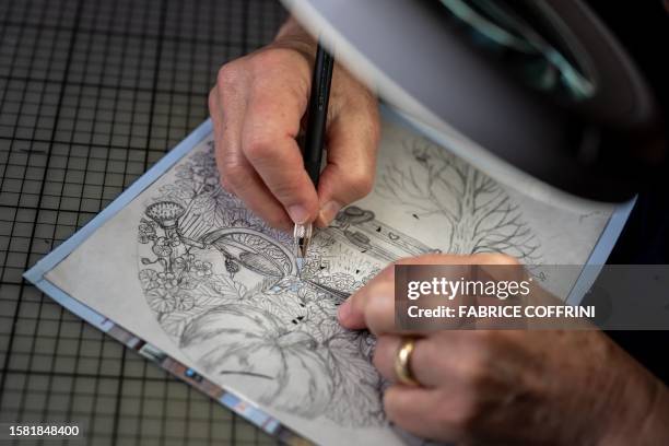 Swiss paper cutting artist Marianne Dubuis works on a piece at her home, in Chateau d'Oex, in the Prealps in western Switzerland on July 25, 2023....